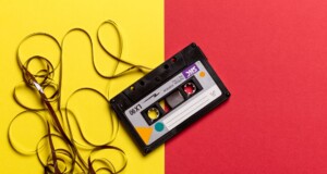 cassette negro con la cinta afuera sobre un fondo amarillo y rojo
