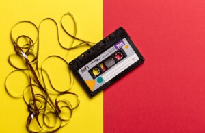 cassette negro con la cinta afuera sobre un fondo amarillo y rojo