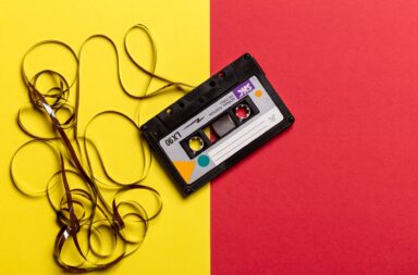 cassette negro con la cinta afuera sobre un fondo amarillo y rojo