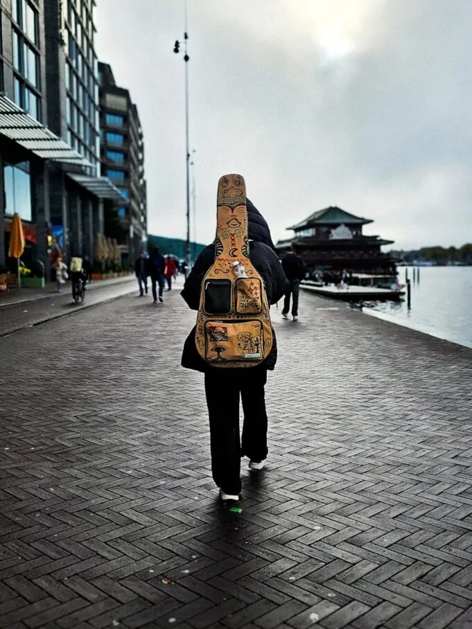 musician walking with guitar by waterfront